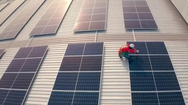 Binanın çatısına güneş panelleri kuran kasklı bir erkek işçi.