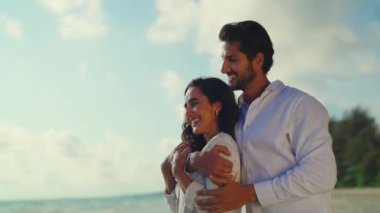 Mutlu ve neşeli bir çift kumsalda sarılıyor.