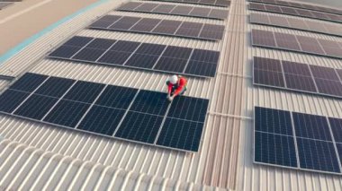 Binanın çatısına güneş panelleri kuran kasklı bir erkek işçi.