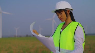 Beyaz şapkalı güzel kadın elinde kağıt projesiyle yel değirmeninin arka planında