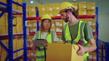 Fabrikada koruyucu üniformalı ve kasklı depo çalışanları var.