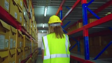 Fabrikada koruyucu üniformalı ve kasklı bir depo çalışanı.