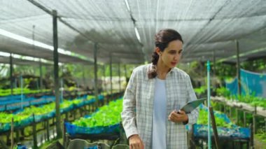 Serada tabletle çalışan genç bir kadın bahçıvan.