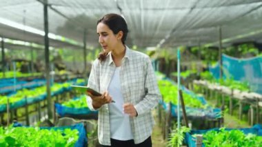 Serada tabletle çalışan genç bir kadın bahçıvan.