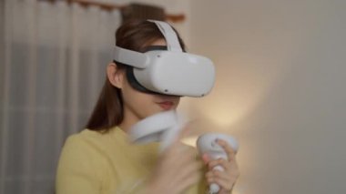 Evde sanal gerçeklik kulaklığı kullanan genç bir kadın.