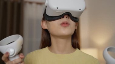 Evde sanal gerçeklik kulaklığı kullanan genç bir kadın.