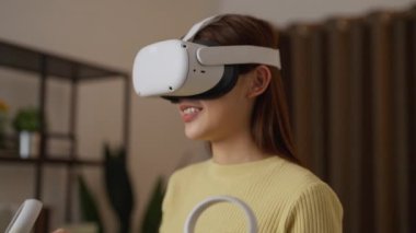 Evde sanal gerçeklik kulaklığı kullanan genç bir kadın.
