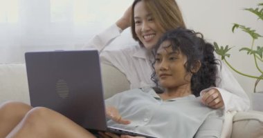 Genç aşıklar kanepede dizüstü bilgisayarlarıyla oturuyorlar.