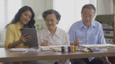 Torunlarıyla birlikte evde resim çizen kıdemli bir adam ve kadın.