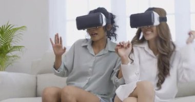 Oturma odasında sanal gerçeklik kulaklığı kullanan iki genç kadın.