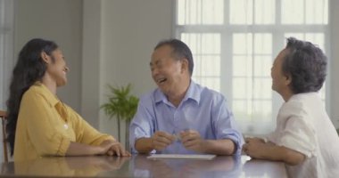 Torunlarıyla birlikte evde masa üstü oyunları oynayan kıdemli bir adam ve bir kadın.