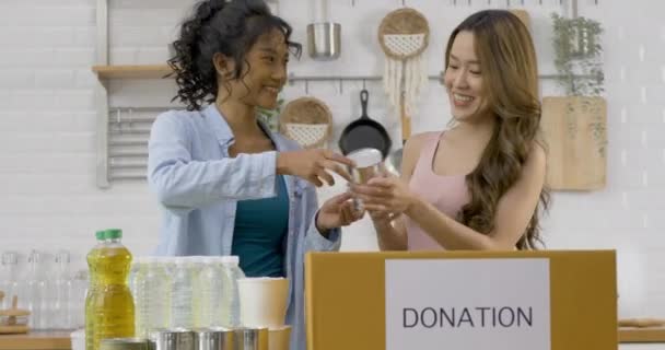 Unga Kvinnor Paketera Produkter Till Donationsrutan Bordet — Stockvideo