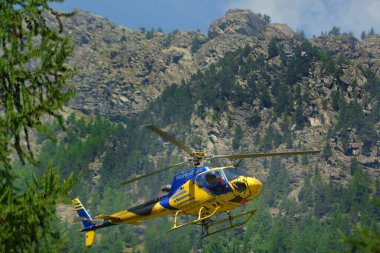 Aosta Vadisi, İtalya 07-18-2022 Bir kargo helikopteri dağ manzarasında uçuyor