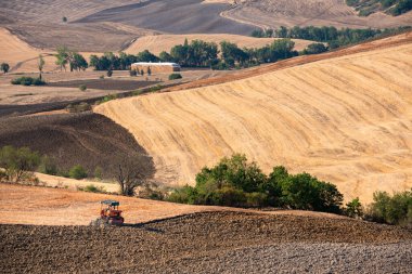 Tractor working on farming lands, countryside landscape