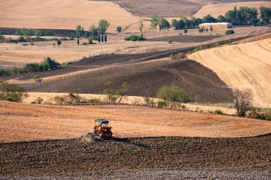 Tractor working on farming lands, countryside landscape