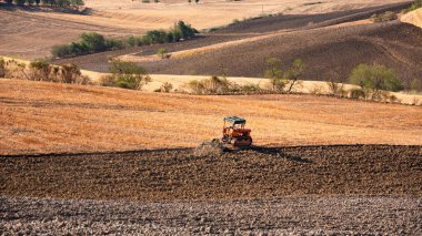 Tractor working on farming lands, countryside landscape