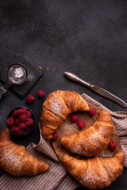 Baked sweet croissant with fresh fruit on dark background