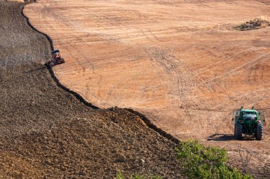 Tractor working on farming lands, countryside landscape