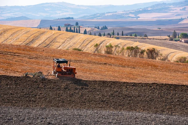 Tractor working on farming lands, countryside landscape