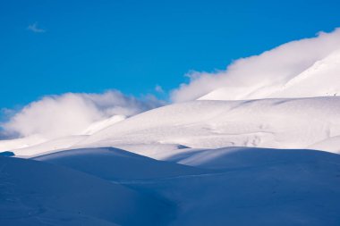 Güzel güneş ışığı ve gölgeler kar tepelerinde ve bulutlarda kontrasttır.