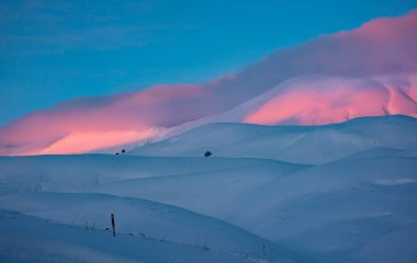 Pembe bulutlu kar tepelerinde güzel kış günbatımı