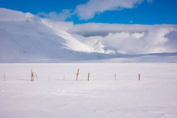 stock image Winter landscape, wooden fence in snow valley on sunny day