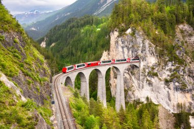 İsviçre kırmızı treni, manzaralı bir yolculuk için dağda viyadük üzerinde