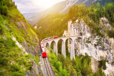 İsviçre kırmızı treni, manzaralı bir yolculuk için dağda viyadük üzerinde