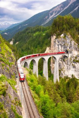 İsviçre kırmızı treni, manzaralı bir yolculuk için dağda viyadük üzerinde