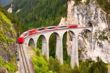 İsviçre kırmızı treni, manzaralı bir yolculuk için dağda viyadük üzerinde