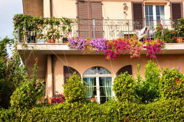 Farklı renklerde çiçeklerle süslenmiş bir balkon.
