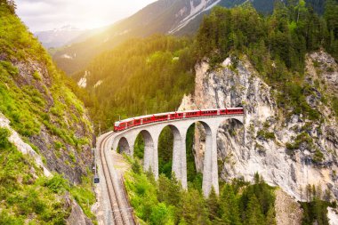 İsviçre kırmızı treni, manzaralı bir yolculuk için dağda viyadük üzerinde