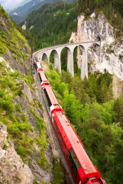 İsviçre kırmızı treni, manzaralı bir yolculuk için dağda viyadük üzerinde
