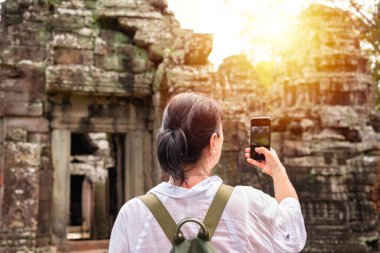 Kadın turist Kamboçya 'daki Angkor tapınağının fotoğrafını çekiyor.
