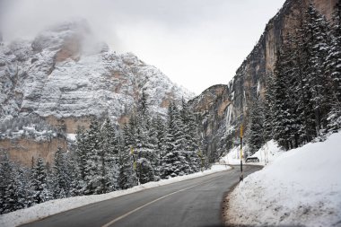 İtalya 'daki Dolomite dağlarında ormanların arasında kış yolu