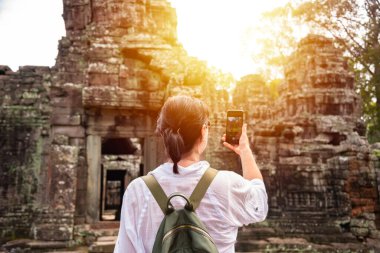 Kadın turist Kamboçya 'daki Angkor tapınağının fotoğrafını çekiyor.
