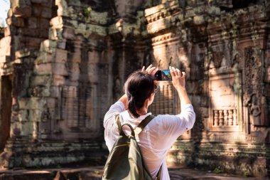 Kadın turist Kamboçya 'daki Angkor tapınağının fotoğrafını çekiyor.