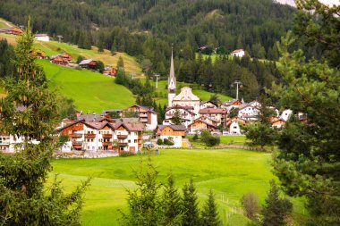 Dolomite Alpleri 'nde bir kilisesi olan dağ köyü Yazın yeşil çayırlarda