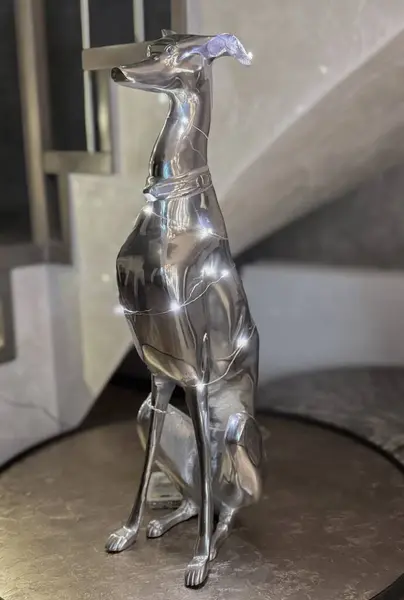 Minimalizmde çelikten yapılmış şık bir köpek heykeli. Noel için kurdeleyle süslenmiş..