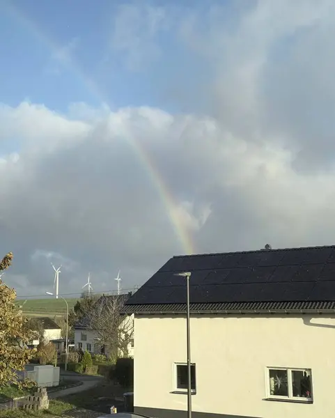 Yağmurlu hava, bulutlar, gökkuşağı ve bir evin ıslak çatısı..