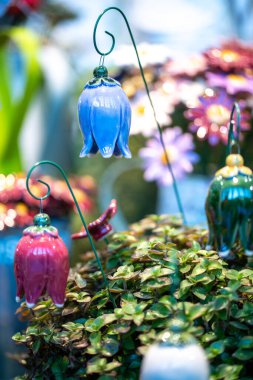 Birkaç çan çiçeği mavi, kırmızı yeşil, kavisli kil veya seramik kablolara bağlanmış, çok iyi işlenmiş.