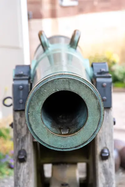 A gun barrel from the front, the camera looks down the barrel. The gun carriage is also made of wood and metal. You can clearly see green corrosion on the metal
