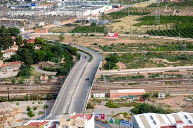 Sagunt, Valencia - İspanya - 09-07-2021: Sagunt 'taki bir otoyolun panoramik görüntüsü, tren raylarının üzerinden geçiyor ve kavşakta bitiyor. Yolda sadece birkaç araba var..