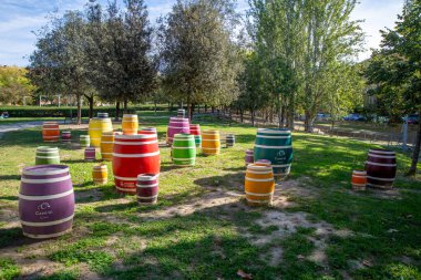 Vilafranca del Penedes, Barcelona - İspanya - 10-30-2023: Bir sanat objesi olarak parktaki yeşil bir alanda beyaz halkalardan yapılmış birkaç renkli varil. Fıçıların farklı boyutları var..