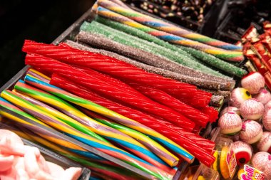 Parlak renkli uzun çubuklar şeklinde şekerler, şeker taklidi gözler, sıralanmış ve satışa hazır.