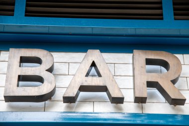 Bronz harflerle yazılmış bir faşada Tapas kelimesi. Duvar beyazla kaplıdır. Mektupların biraz gölgesi olacak.