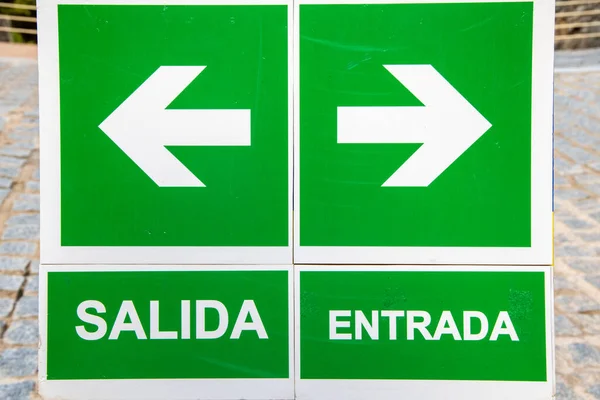 A collection of signs in the Spanish language. On the left side, there are two signs, one with an arrow and the other with the word \
