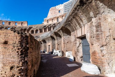 Roma, Latium - İtalya - 11-23-2022: Duvarlarda kemerler ve mavi gökyüzünün altında yer alan sermaye parçalarıyla Kolezyum 'un duvarları arasında geçiş