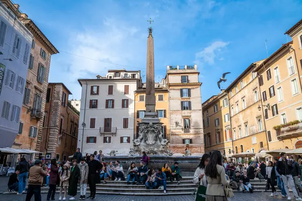 Roma, Latium - İtalya - 11-21-2022: Piazza della Rotonda 'da hayat dolu Roma meydanı, İtalya' da halka açık alanların klasik bir örneği olan Fontana del Pantheon 'un tarihi çeşmesi ve dikilitaşını çevreledi
