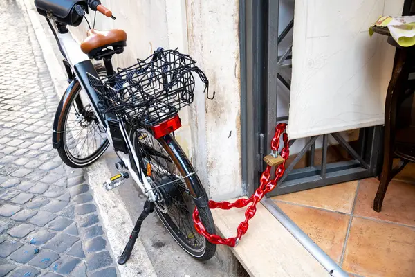 Urban security: a bicycle locked with a red chain outside a cafe, highlighting theft prevention measures